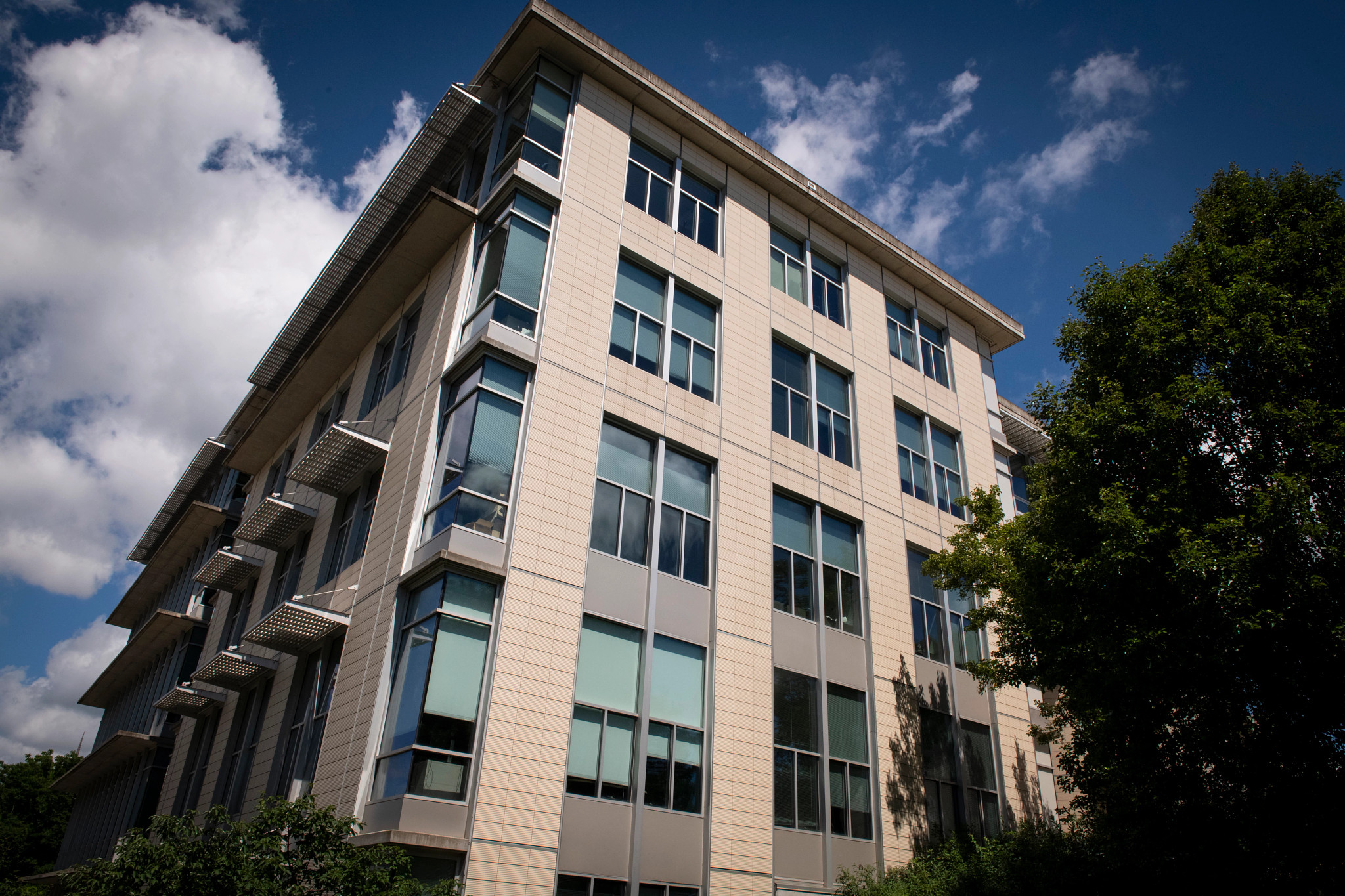 Photo of a modern building in front of blue sky and white clouds.